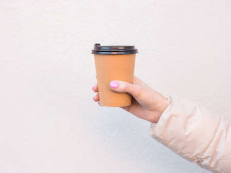 Woman hand holding empty paper coffee cup outdoor. Template mock up
