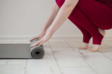 Yoga at home active lifestyle woman rolling exercise mat in living room for meditation yoga. Indoor...