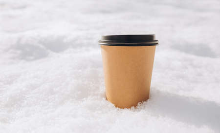 Hot paper Craft cup of coffee on the snow on a morning. Take away or delivery concept. Copy space. Winter lifestyle. Place for your text or mug, mockupの写真素材