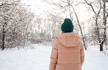 Young beautiful happy girl in winter green knitted hat posing in winter forest. Snow backgroundの写真素材