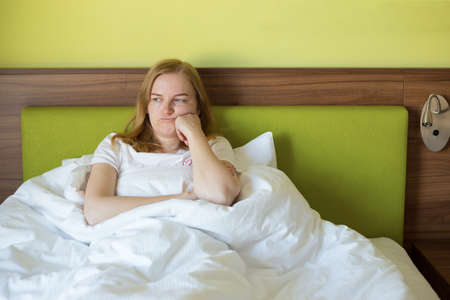 Close up young blonde woman feeling upset, sad, disappoint crying lonely in green bedroom. Emotional...
