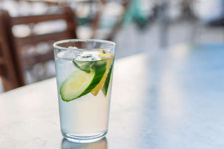 Lemonade with lemons and cucumber on black table over city background. Glass of Cold drinks. Concept of proper nutrition and healthy eating. Fitness diet.の写真素材