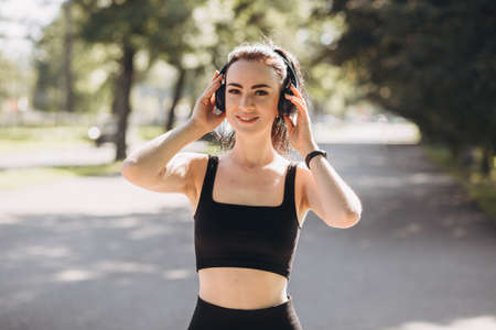 Athletic young happy woman runing with headphones in the park, jogging in the morning for lifestyle...