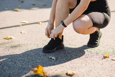 Fitness woman tying shoelaces outdoors. Tie sneakers. Sport and healthy active lifestyle concept....