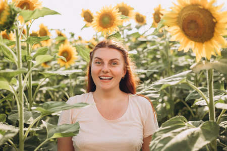 Happy Smiling female standing in sunflowers field on summer day. Harvest time. Summer vacationの写真素材