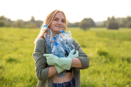Woman collect plastic bottles on the grass in the park. Global problem of environmental pollution. Plastic problem and failure or disposal and recycling. Eco friendly. Go greenの写真素材