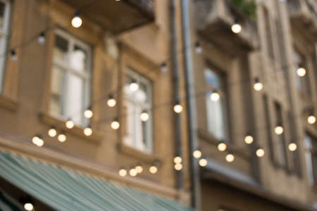 Decorative outdoor string lights at morning time, Defocused Background, city life backdrop, party time with Yellow bokeh ballsの写真素材