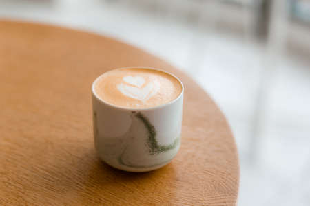 One Cup of cappuccino with latte art. Coffee in white cup on brown wooden table in cafe. Concept of easy breakfast.の写真素材