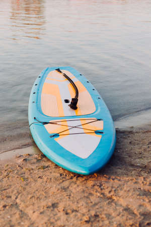 Blue Surf board on beach background. Surfing and SUP boarding equipment in sunset lights close-up....