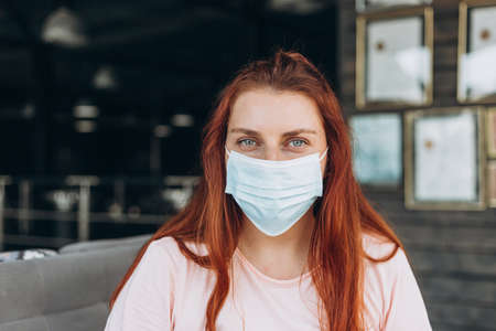 A happy woman in a protective medical mask on her face sits at the airport waiting for a flightの写真素材