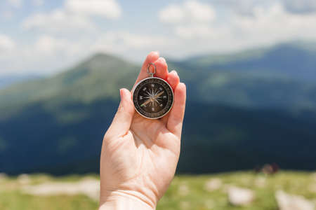 Woman holding a compass in hand on nature background, ready to travel, keep calm. Tourism, traveling, hiking and healthy lifestyle concept.の写真素材
