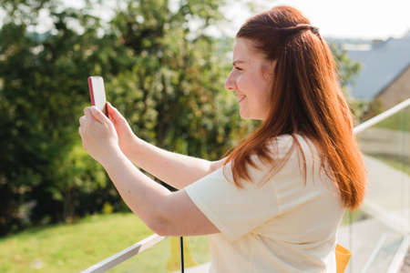 Lovely woman making selfie while walking modern building. Carefree and happy, sunny summer mood....