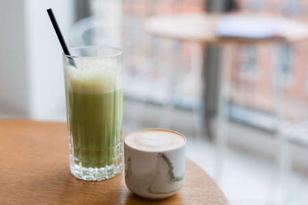 Matcha and Cup of cappuccino with latte art on wooden table in cafe. Concept of easy breakfast. Food...