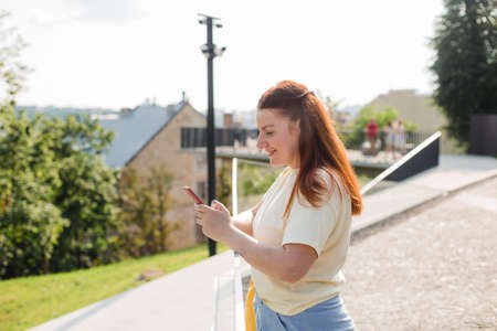 Portrait of positive cheerful girl with tote bag use smart phone share social media news over nature...