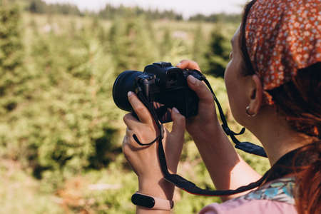 Portrait of beautiful laughing woman making photos at summer green park. Hiking in nature. Travel conceptの写真素材
