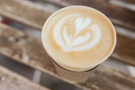 Soft focus of Latte art hot coffee in eco paper cup on table background. Street coffee, top view.
