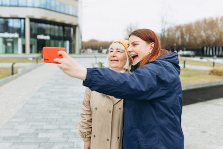 Happy Mother and adult positive daughter are doing Selfie on city street, Urban lifestyle concept....