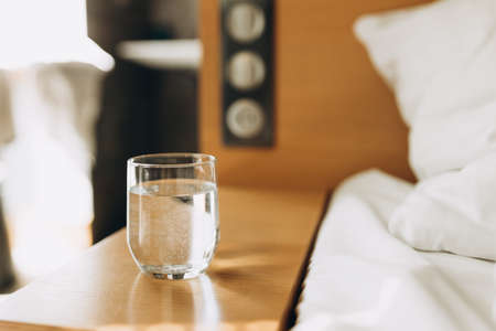Glass of water on wooden table bokeh background. Good habit - drinking a glass of water before going...
