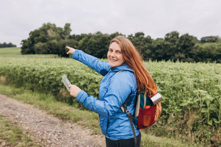 Happy woman with backpack and map standing on nature background. Girl search of new adventures....