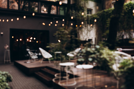 Blurred background of outdoor restaurant with abstract bokeh light. Outdoor cafe with tables and chairs. Defocused Backgroundの写真素材