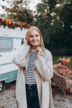 Stylish blond woman wearing coat in nature background. Elegance at fall season outdoors. Trendy female clothing, autumn fashion collection.の写真素材