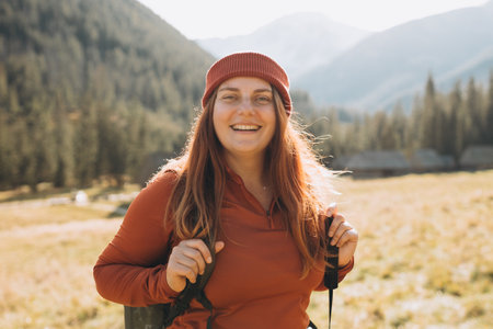 Happy redhead person in active trekking clothes with backpack walking on nature backgraund. Travel and active lifestyle concept. Amazing chill momentの写真素材