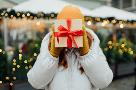 Happy young beautiful woman holding a Christmas gift in front of her face. Winter holidays sale. Concept of shopping, holidays and happiness Christmas.の写真素材