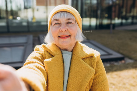 Beautiful senior blonde woman taking selfie on sity street. Looking at camera and smile. Travel and...