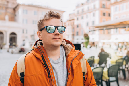 Cropped shot of a handsome man traveling through the city. Young men in sunglasses with a yellow backpack walking along on city street backgroundの写真素材