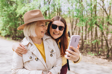 Two women together wear casual clothes doing selfie shot pov on mobile cell phone. Family day concept. Young woman and senior middle aged mom spending time togetherの写真素材