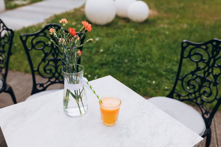 Full glass of orange juice close-up. Fresh orange juice on marble table on the cafe terrace on the street. Glass of yellow lemonade in a summer cafe. Selective focus.の写真素材