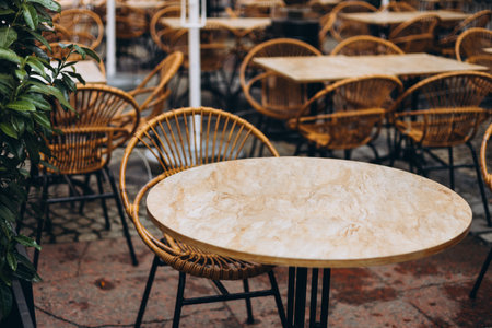 Outdoor street cafe tables ready for service. Empty cafe terrace with stone table and rattan chair, morning time. Food conceptの写真素材