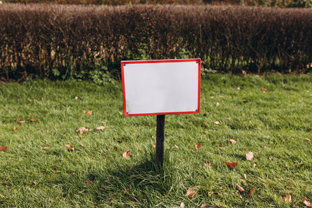 Closeup white metal sign at green grass background, nameplate with a space for your text. Horizontal bannerの写真素材