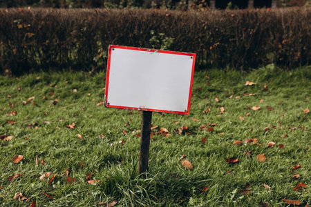 Closeup white metal sign at green grass background, nameplate with a space for your text. Horizontal bannerの写真素材