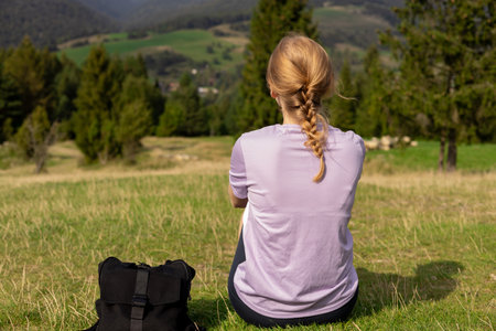 Back view of Woman in active trekking clothes having a halt after hiking. Travel and active...