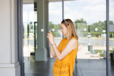 Beautiful female tourist taking photo with mobile phone on urban background. Urban lifestyle...