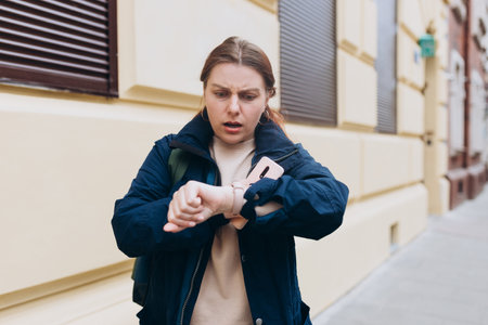 Frustrated and angry young woman, who waiting for a friend who late for an appointment. Urban...