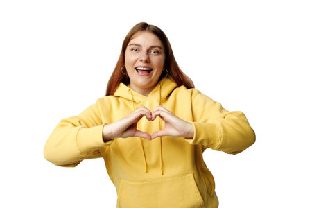 Attractive 30s brunette young woman feels happy and romantic shapes heart gesture expresses tender...