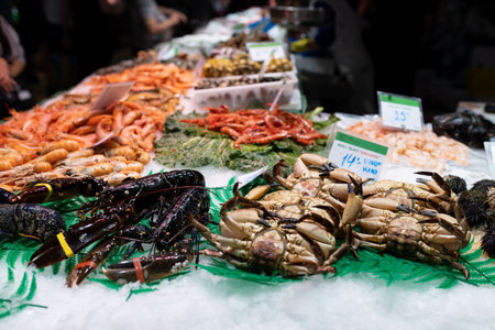 Fresh lobster, shrimps, crabs, sea urchin and other seafood on market counter. Food stalls at La Boqueria market in Barcelonaの写真素材