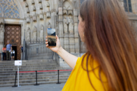 Young traveling woman taking photo near the famous saint Eulalia church in Barcelona. Concept of travel, tourism and vacation in city. Use technology conceptの写真素材