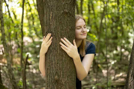 Happy beautiful woman love nature hugging a pine tree. Caring for the environment. The ecology concept of saving the world and love nature by human. Earth Day.の写真素材