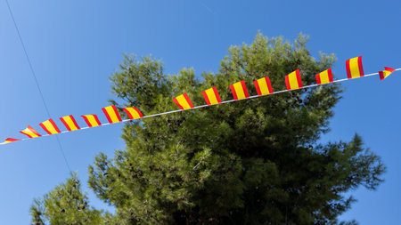 Spanish flags flap under the gusts of wind on the background of blue sky. Travel and tourism in...