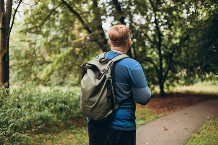 One Caucasian male hiking in the woods. Travel, active lifestyle, people and hobby concept. Rear...