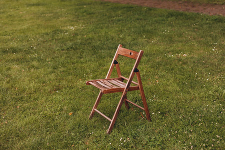 Empty wooden chair on the green lawn. Theme of loneliness.の写真素材