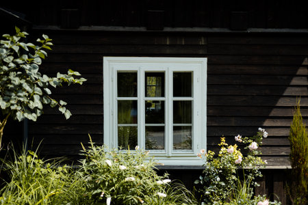 Exterior wood wall with with painted white framed window. Old window in wooden cottage