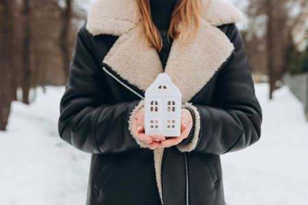 close up of hands holding white ceramic house. Family, building, construction, real estate and safety conceptの写真素材