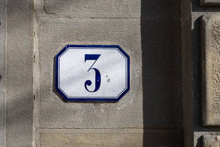 Decorative ceramic house number 3 tile on the wall, characteristic decorative element outdoors
