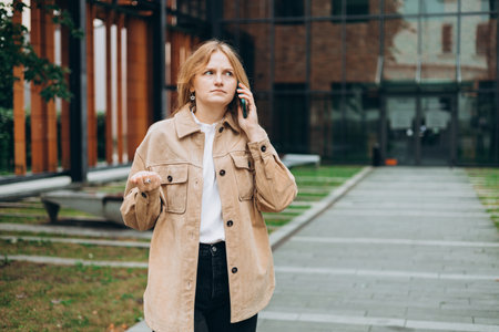 Angry woman on cell phone walking outside building. Frustrated woman talking on phone. Summer time. Negative people emotionの写真素材