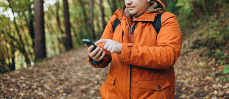 Young Caucasian 30s man backpacker with smartphone catching signal at wooden forest. Road trip, transport, travel, technology and people concept. High quality photoの写真素材
