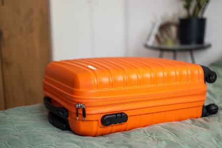 Big orange suitcase on the bed in light room. Baggage case packing getting ready to travel trip vacation. Lifestyle, adventure and tourism concept.の写真素材